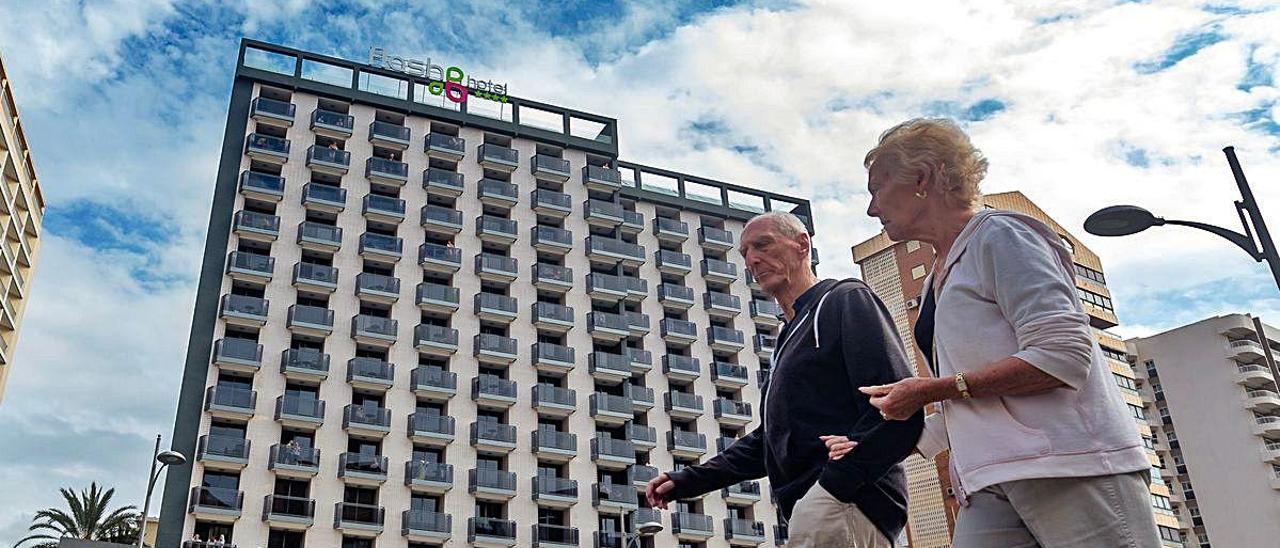 Dos turistas pasean por Benidorm. Al fondo, un hotel.