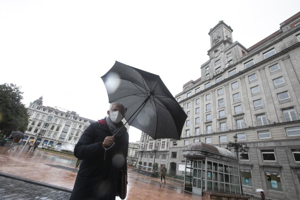 Un hombre bajo la lluvia en Oviedo.