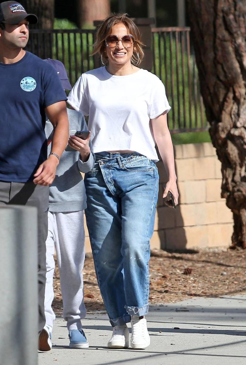 Jennifer Lopez con vaqueros de original cierre cruzado, camiseta blanca y zapatillas blancas