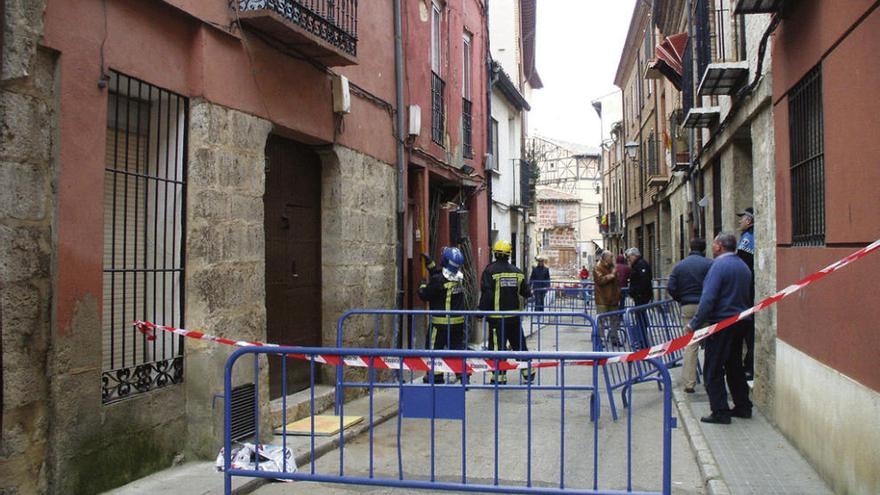 Bomberos apuntalan el edificio hundido, ante la mirada de técnicos municipales y vecinos.