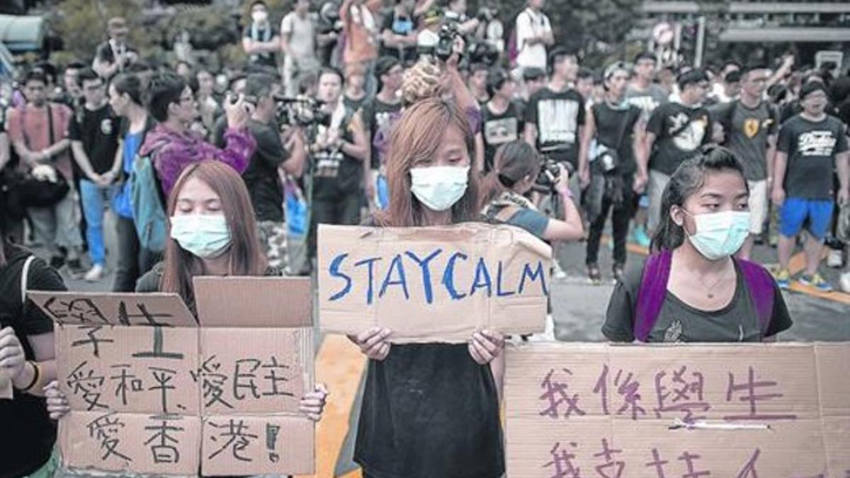 Manifestantes prodemocracia en Hong Kong muestran pancartas en el Día Nacional de China, ayer.