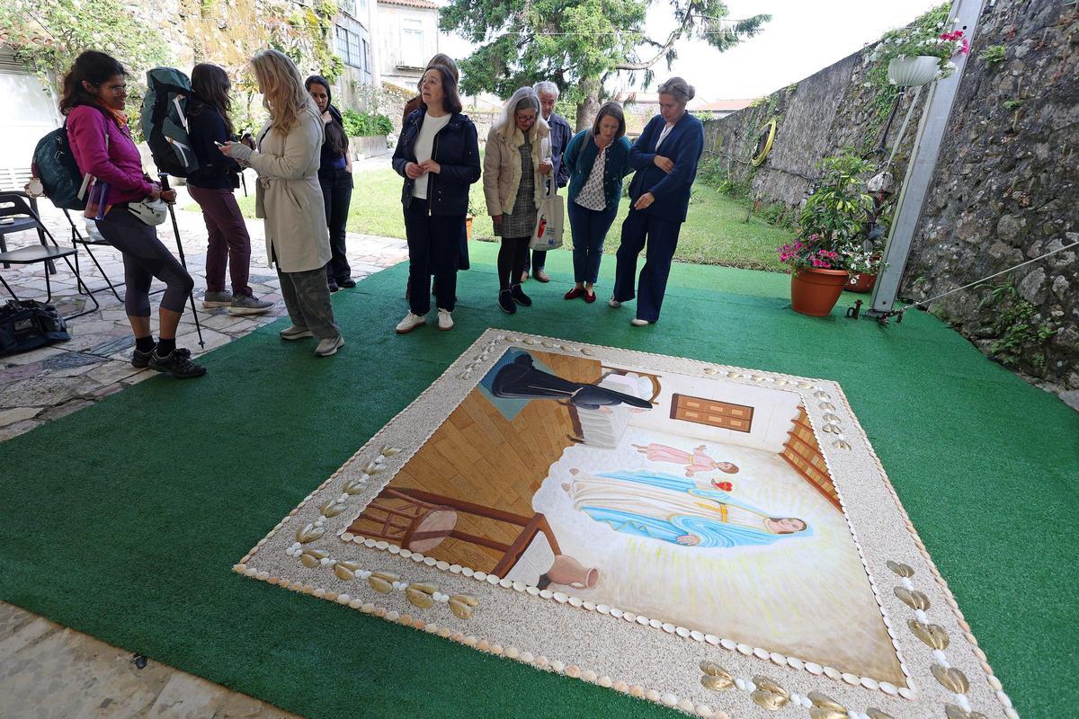 Varias personas observan la alfombra, en el patio del edificio.