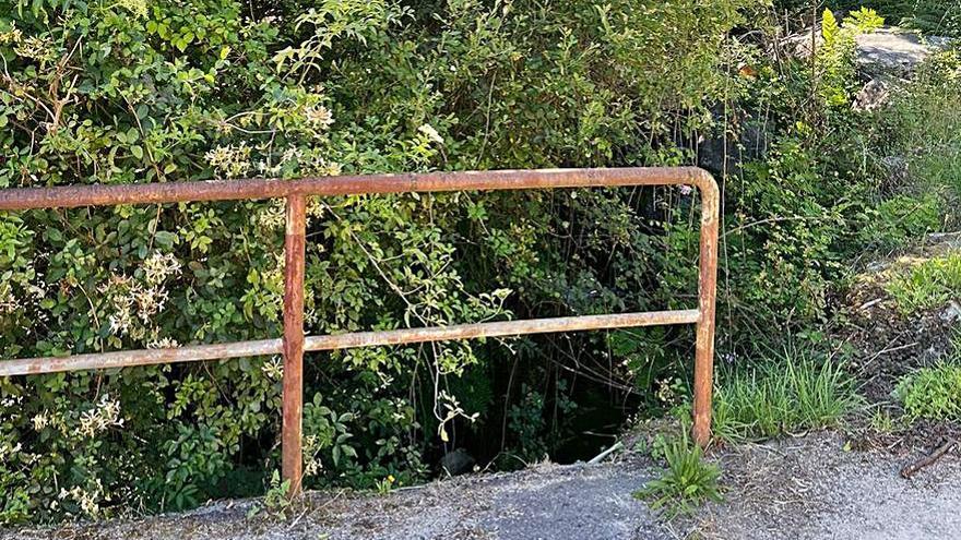 La maleza impide ver el río en un puente.