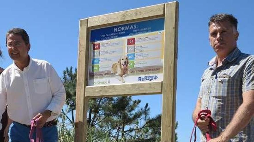 Miguel Pérez y Alfredo Bea, junto a dos perros y un cartel.  // Muñiz