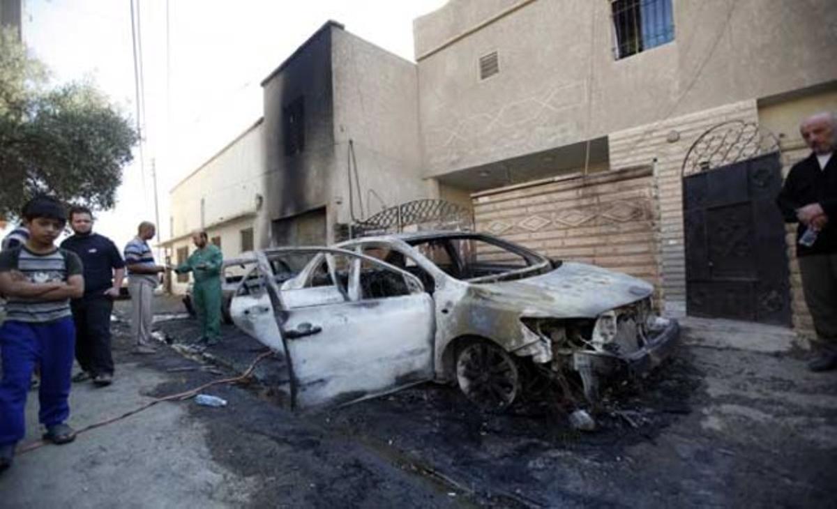 Habitants del cèntric barri de Karrada, a Bagdad (Iraq), observen les restes d’un vehicle després d’un atac bomba. Dues bombes han explotat avui en aquest districte i han matat dos cristians i n’han ferit quatre, segons fonts del Ministeri de l’Interior.