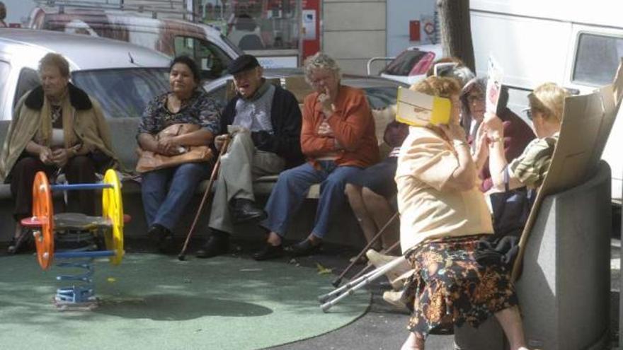 Mayores sentados en la plaza de As Conchiñas un día de sol. / víctor echave