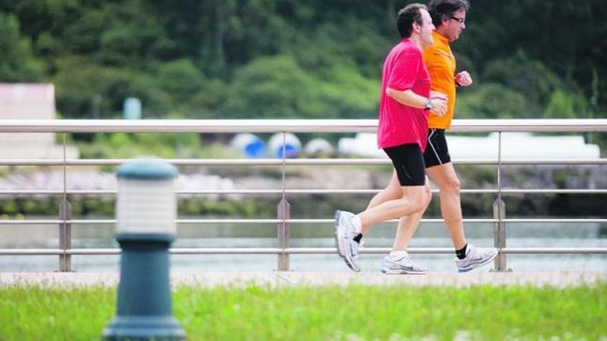 Dos hombres hacen «footing» por el paseo de la ría.