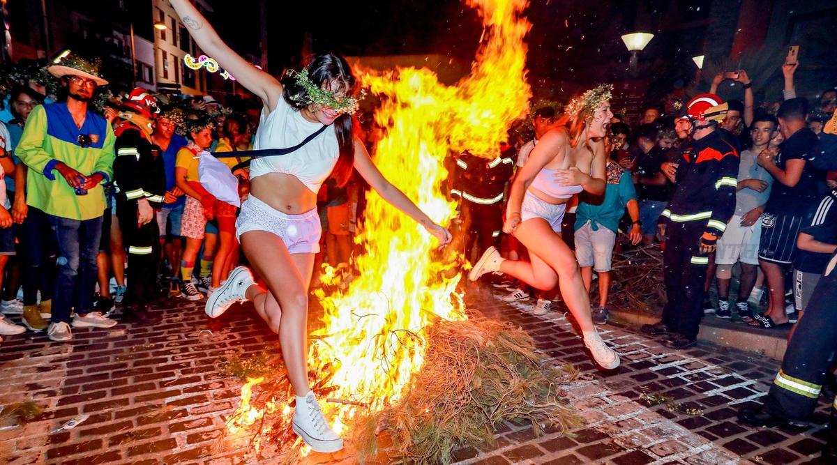 Dos jóvenes que portan coronas de "vidriella" saltan una hoguera en las fiestas del pasado año
