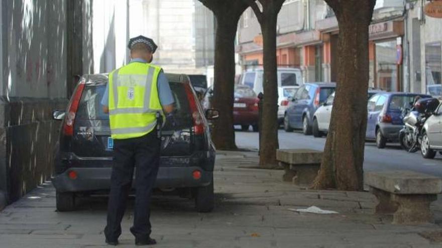 Un policía local multa a un coche mal aparcado en el mercado de San Agustín. / carlos pardellas