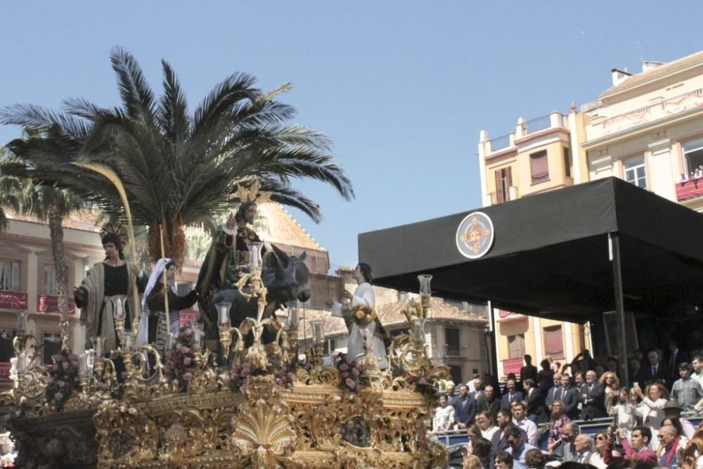 La Semana Santa de 2019 llevaba aparejada una gran novedad: la implementación del nuevo recorrido oficial, que comenzaba en la plaza de la Constitución, junto a la Tribuna Oficial, y continuaba con el discurrir por calle Larios en sentido inverso al habitual, calle Martínez, Atarazanas, Ordóñez, Alameda Principal, plaza de la Marina y Molina Lario, concluyendo a los pies de la torre sur de la Catedral. Así, el recorrido oficial aumentaba el trazado hasta los 1.200 metros, casi 400 metros más que el actual, con mayor espacio para recolocar a los 24.000 abonados. Sin embargo, hubo críticas de algunos aforados, insatisfechos con el lugar que les había tocado, y se produjeron imágenes como malagueños atrapados tras una serie de vallas o problemas de movilidad. La Agrupación de Cofradías defiende que el cambio se debió, sobre todo, a motivos de seguridad. De momento, este itinerario continúa a la espera de que los malagueños se vayan acostumbrado paulatinamente a su puesta en marcha. En la imagen, Nuestro Padre Jesús a Su Entrada en Jerusalén en la Tribuna Oficial, una instantánea histórica al ser la primera vez que se producía. La Pollinica fue la primera cofradía en iniciar su estación de penitencia esta Semana Santa, como marcan los estatutos de la Agrupación, algo que en un principio no estaba claro. Debió hacer muchas horas de recorrido.