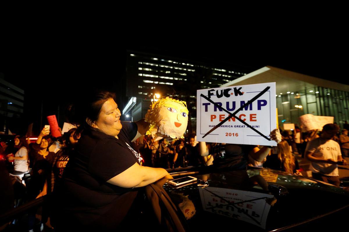 A motorist stops to put out a pinata while protesting the election of Republican Donald Trump as the president of the United States in downtown Los Angeles, California U.S., November 9, 2016.   REUTERS/Mario Anzuoni   TEMPLATE OUT