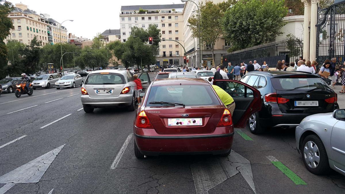 Coches parados en doble fila a la salida de un colegio.