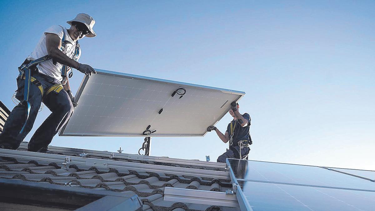 Dos operarios instalan placas solares fotovoltaicas en una vivienda, en Madrid.