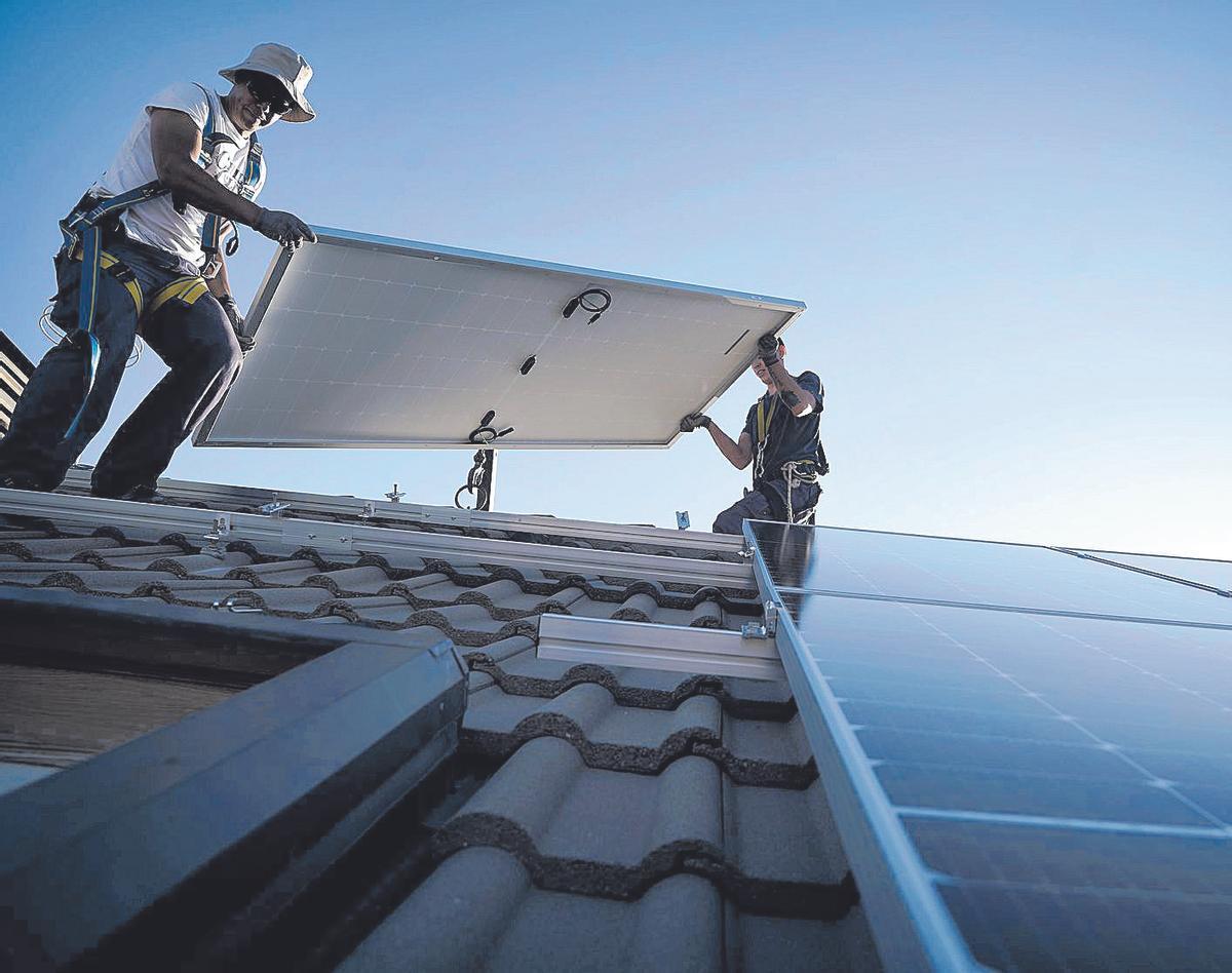 Dos operarios instalan placas solares fotovoltaicas en una vivienda, en Madrid.