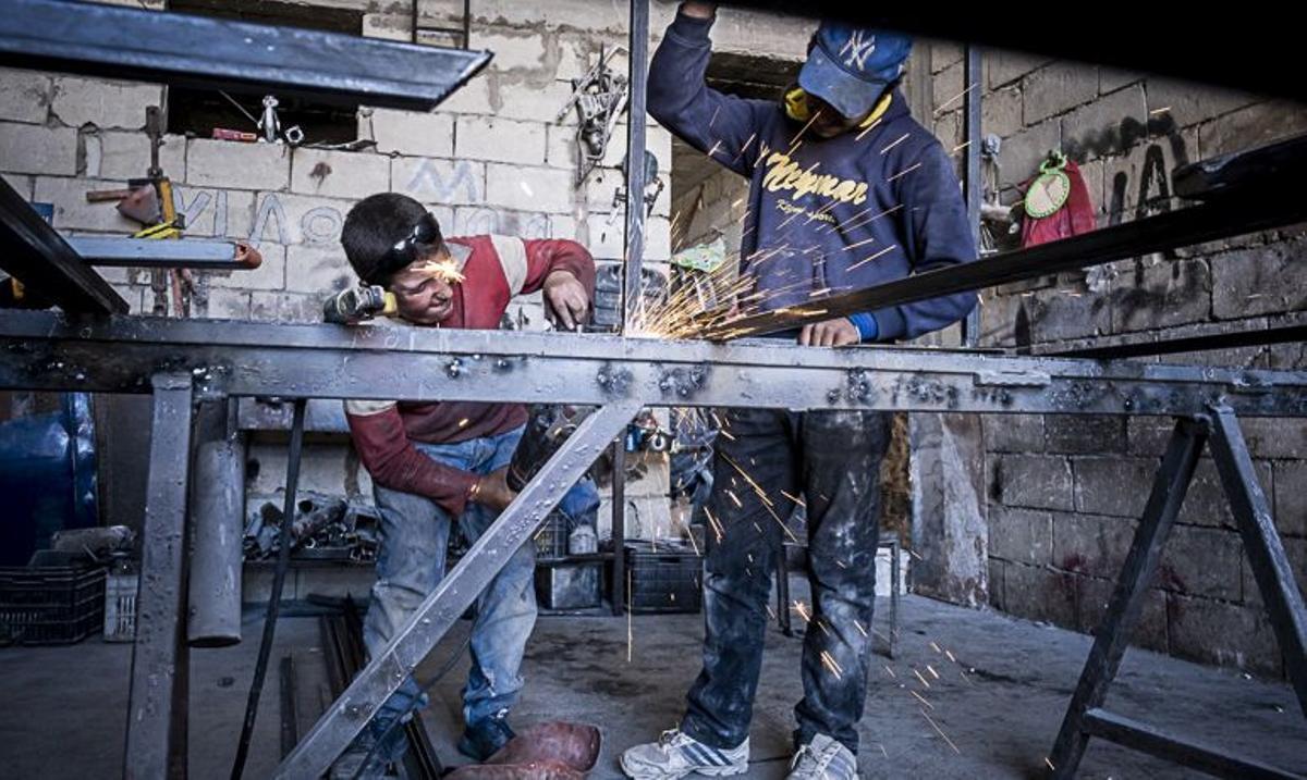 At right Ahmad, 16 years old, and Ahmad, 11 years Old, working with metals and dangerous machinery, child labour, syrian refugees, in Arsal, Bekaa Valley, Lebanon