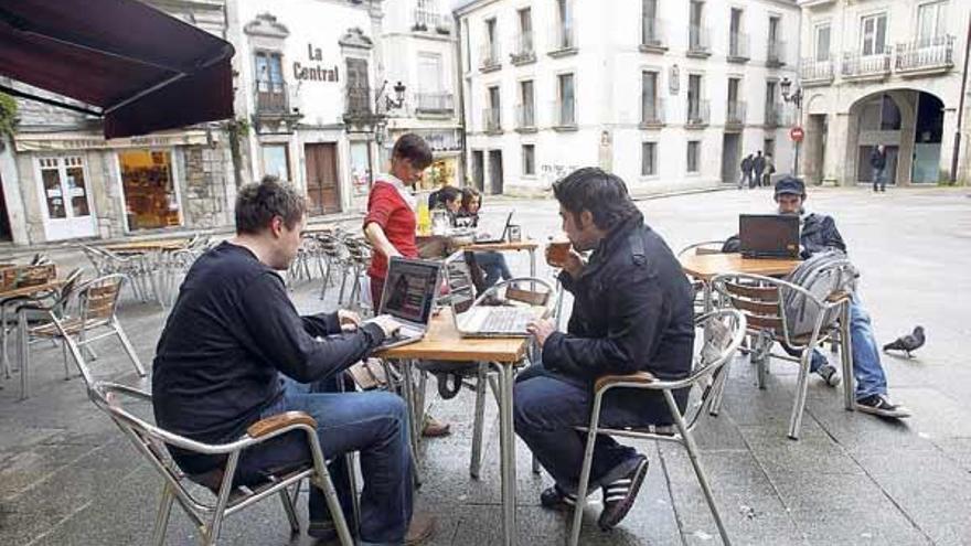 Varios jóvenes se conectan a internet con sus ordenadores desde la Praza da Constitución.