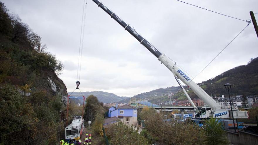 Una grúa trata de encarrilar el tren que se salió de la vía por un argayo en El Entrego