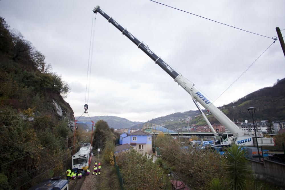 Una grúa trata de encarrilar el tren que se salió de la vía por un argayo en El Entrego