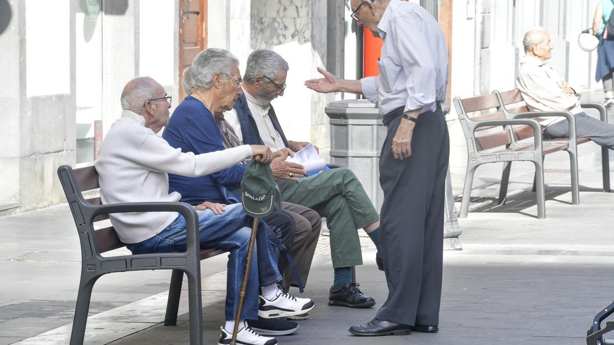 Varios jubilados charlan mientras descansan en un banco.