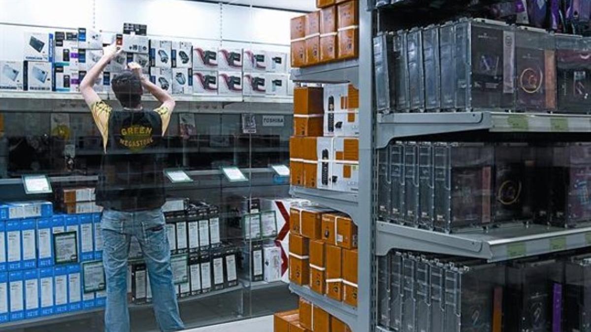 Un trabajador de una tienda de informática de Barcelona coloca nuevos productos en uno de los estantes, ayer.