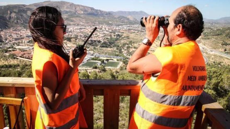 Dos voluntarios vigilan en uno de los tramos de la Vía Verde desde el que se aprecia al fondo el casco urbano.