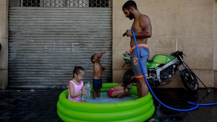 Un padre con sus hijos en un barrio empobrecido de València durante una ola de calor este verano.