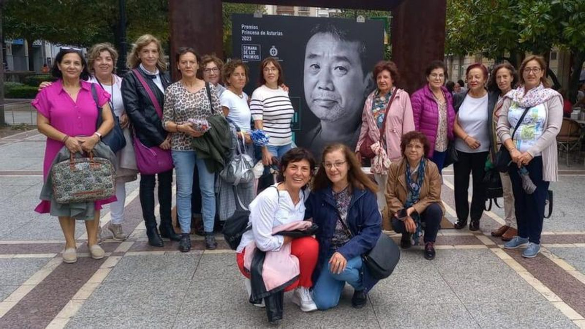 Las participantes en el club de lectura de Campaspero, en Valladolid, posan junto a un retrato de Murakami en Gijón.