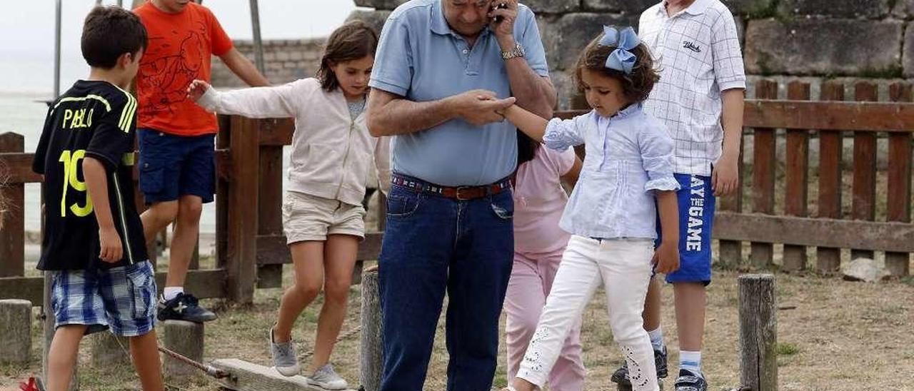 Un abuelo cuida de sus nietos en un parque de Nigrán. // Marta G. Brea