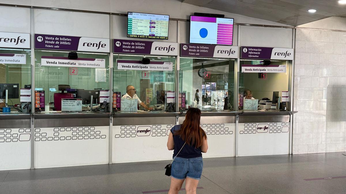 Una noia mira una de les pantalles de Renfe de Girona a les guixetes