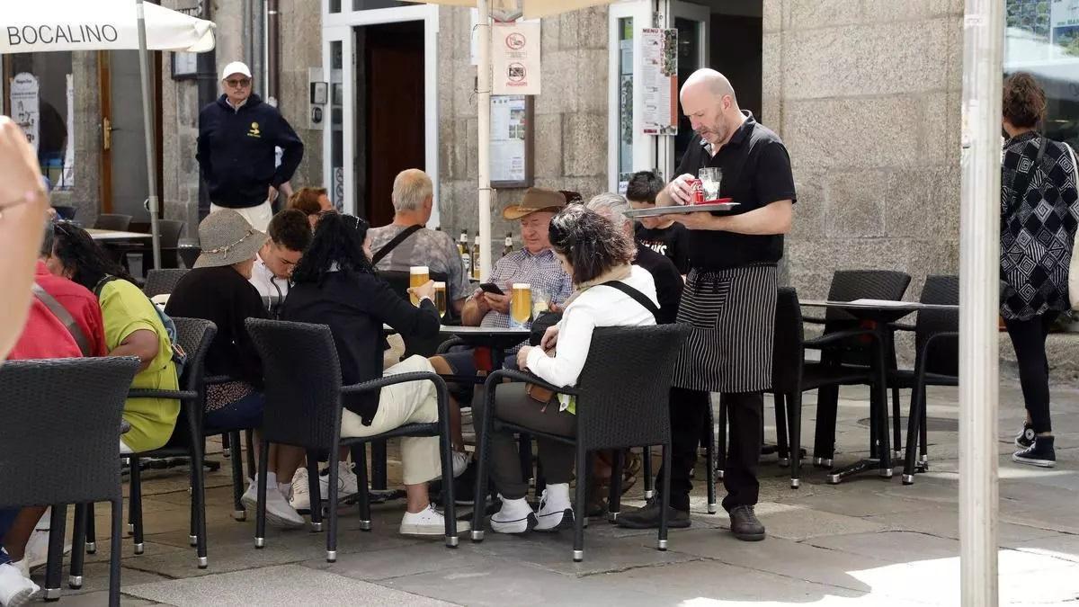 Turistas en la terraza de un establecimiento de hostelería situado en el casco histórico de Santiago de Compostela