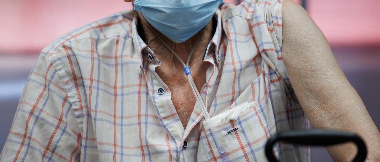 Un hombre mayor prepara su brazo para la inyección de la cuarta dosis de la vacuna frente al covid 19.