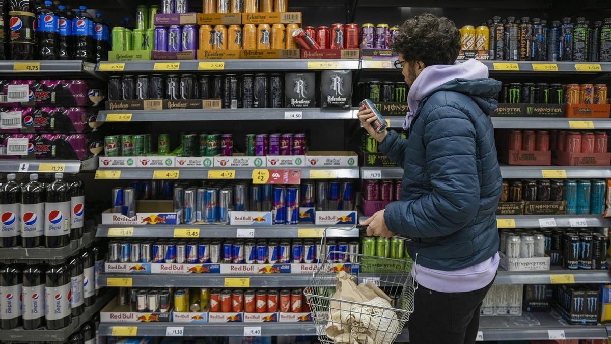 Archivo - Un joven mira la sección de bebidas energéticas en el supermercado.