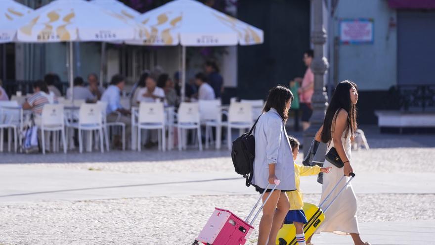 Dos turistas arrastran sus maletas por la ciudad de Cadiz.