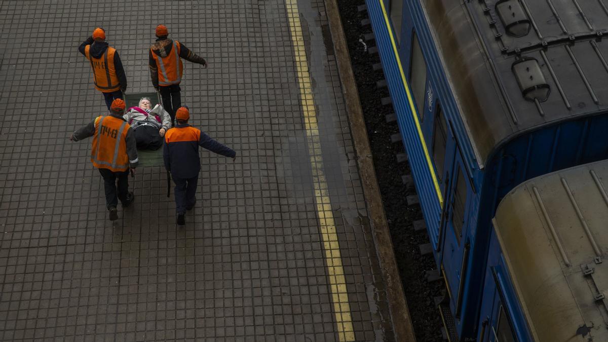 Voluntarios ayudan a evacuar a una persona en camilla en la estación de tren de Pokrovsk en Ucrania