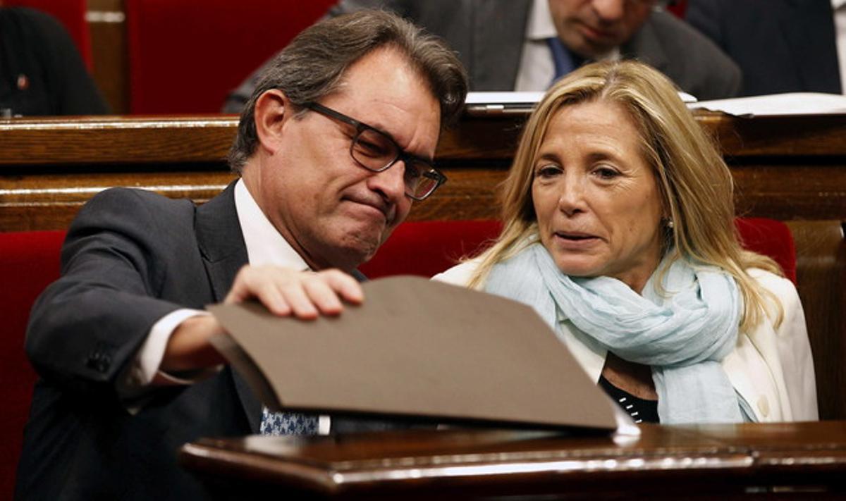 Artur Mas mira a sota d’una carpeta al Parlament, al costat de la vicepresidenta Joana Ortega.