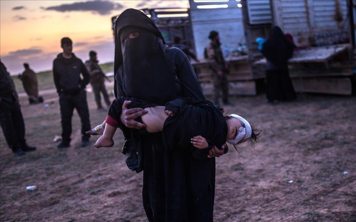 Una mujer transporta a su hija herida mientras camina hacia los miembros de las Fuerzas Democráticas Sirias SDF, lideradas por los kurdos, justo después de dejar el último bastión del Estado Islámico de Baghouz en la provincia oriental de Deir Ezzor.