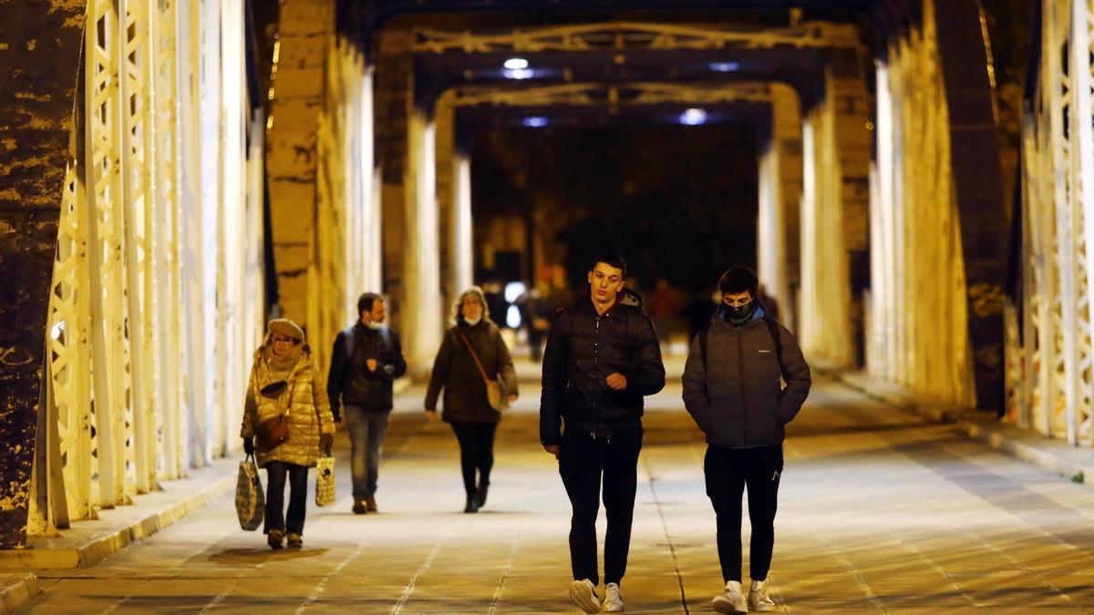 Zaragozanos pasean por el puente de Hierro de la capital aragonesa.