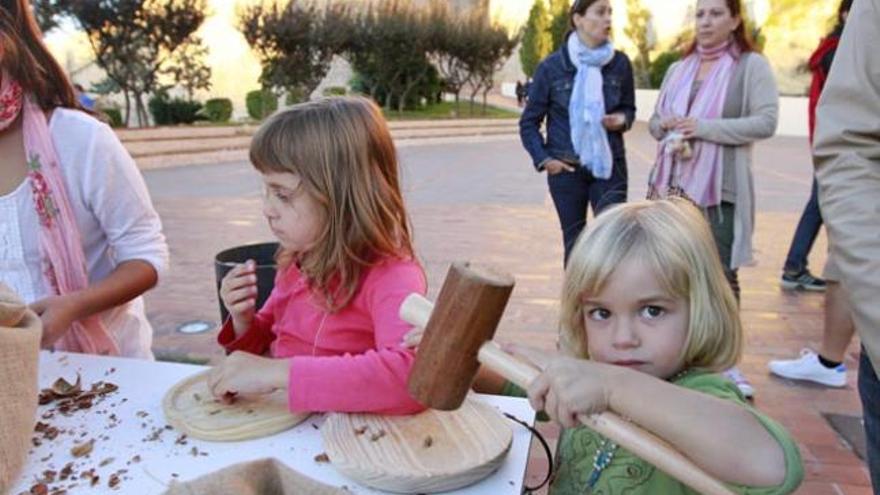 Dos niñas utilizan dos mazas para romper los frutos secos ayer en Portal Nou.