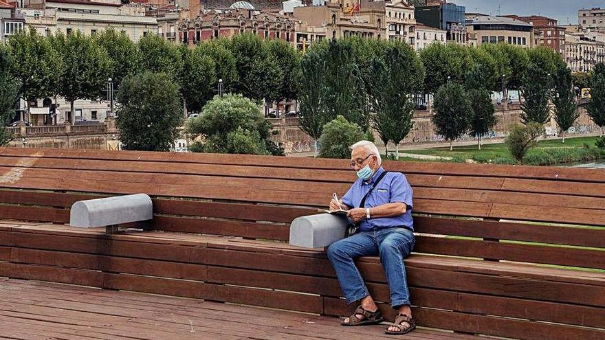 Un home descansa davant del perfil del nucli històric de Lleida