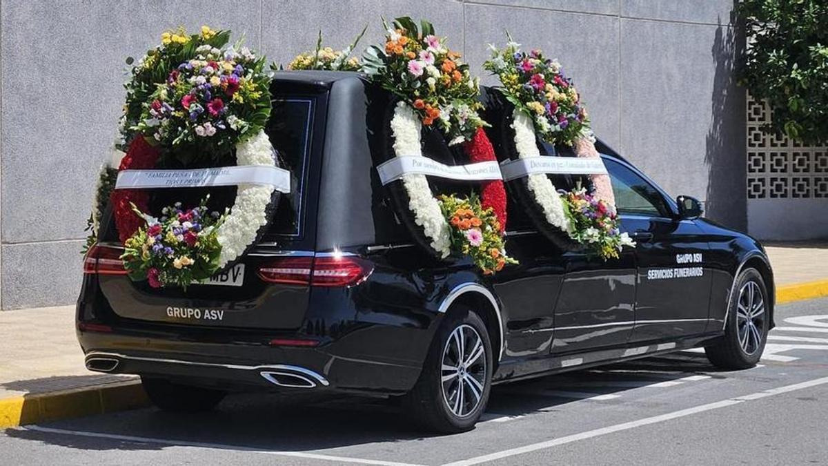 El coche fúnebre cargado de coronas con el féretro del asesino machista.
