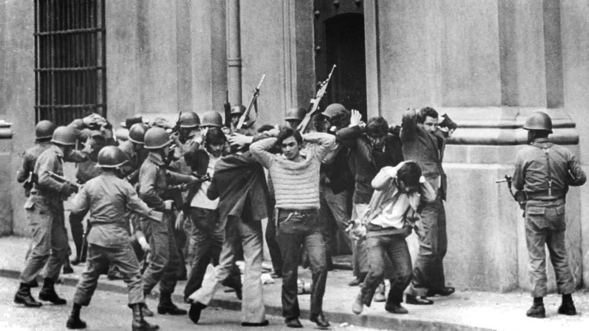 Asesores y trabajadores de Allende salen del palacio presidencial ante los militares.