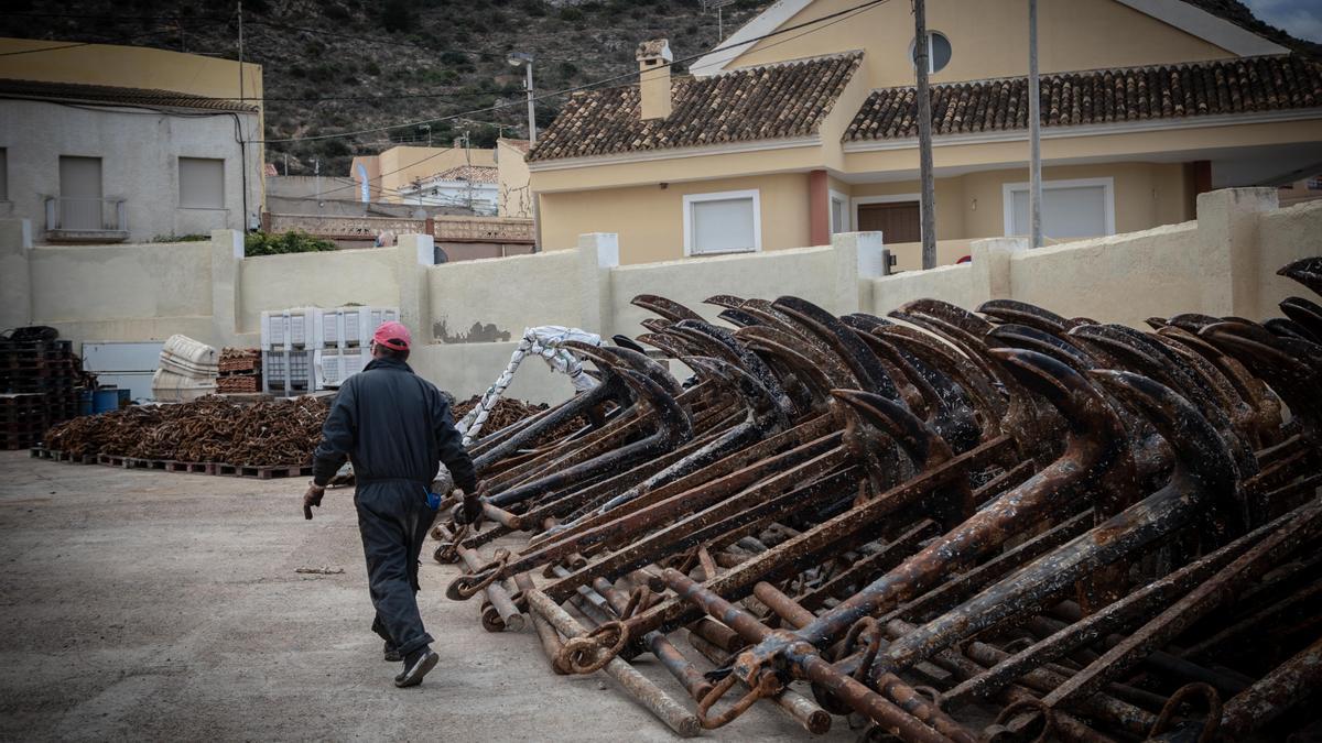 Un pescador junto a una agrupación de anclas.