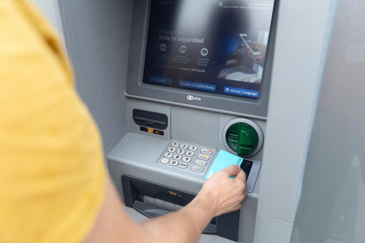 Un hombre utiliza un cajero automático en una imagen de 2024