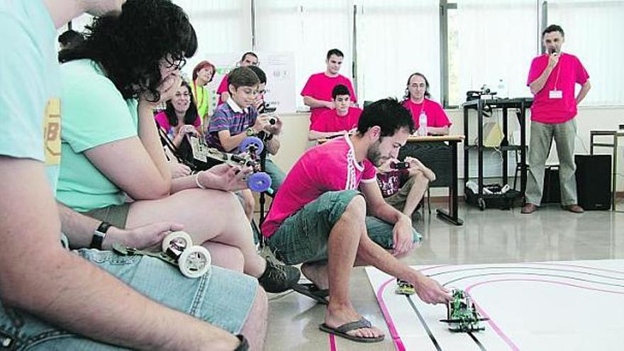 Antonio Hermida pone su prototipo en el circuito de velocidad del campeonato de robótica de la Universidad, ante la mirada del resto de participantes.