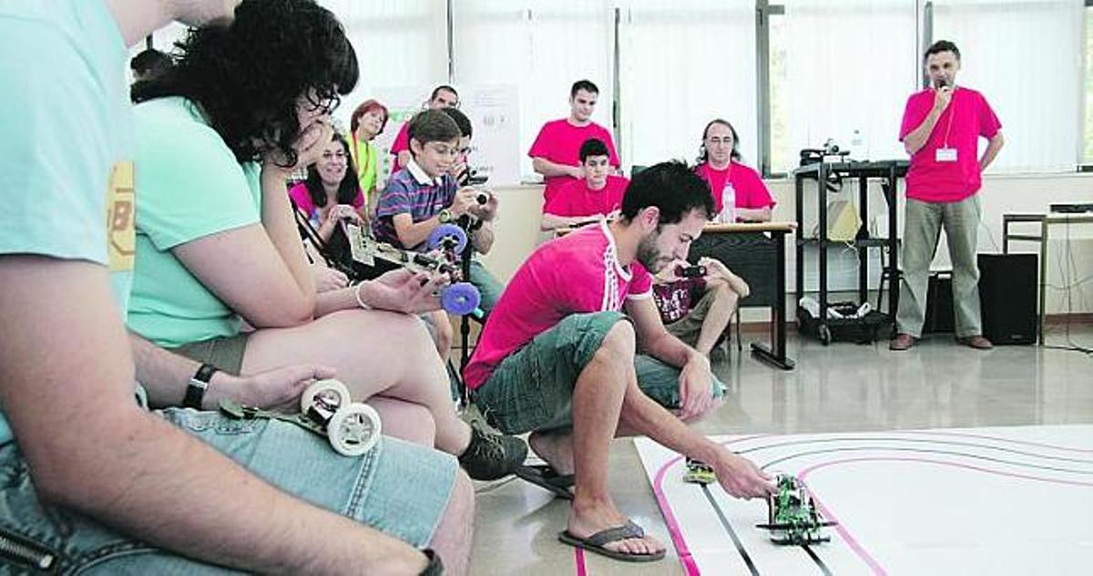 Antonio Hermida pone su prototipo en el circuito de velocidad del campeonato de robótica de la Universidad, ante la mirada del resto de participantes.
