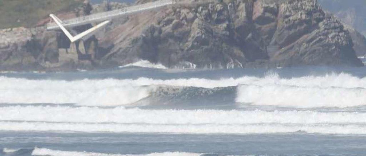 Una mujer pasea con su perro por la playa de Salinas.