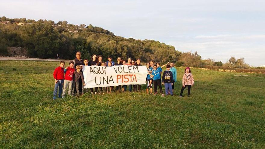 Un grupo de jóvenes deportistas sostiene una pancarta reivindicativa a favor de la construcción de una pista de atletismo.