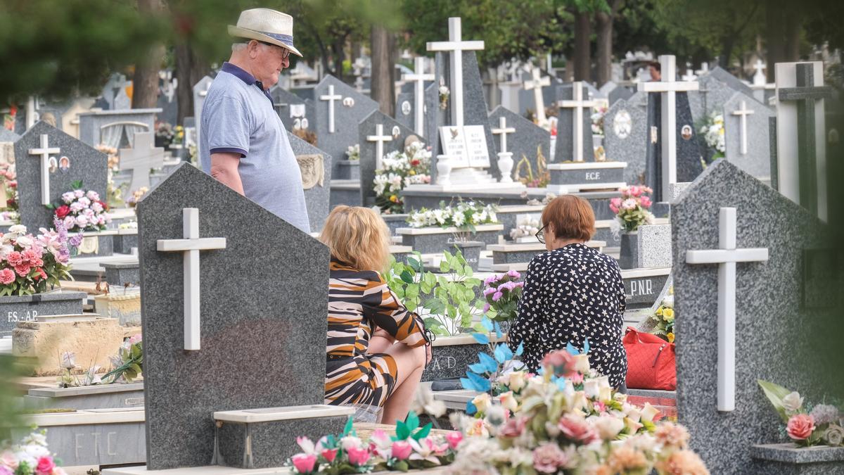 Dos mujeres limpian una lápida en el Cementerio de Alicante.