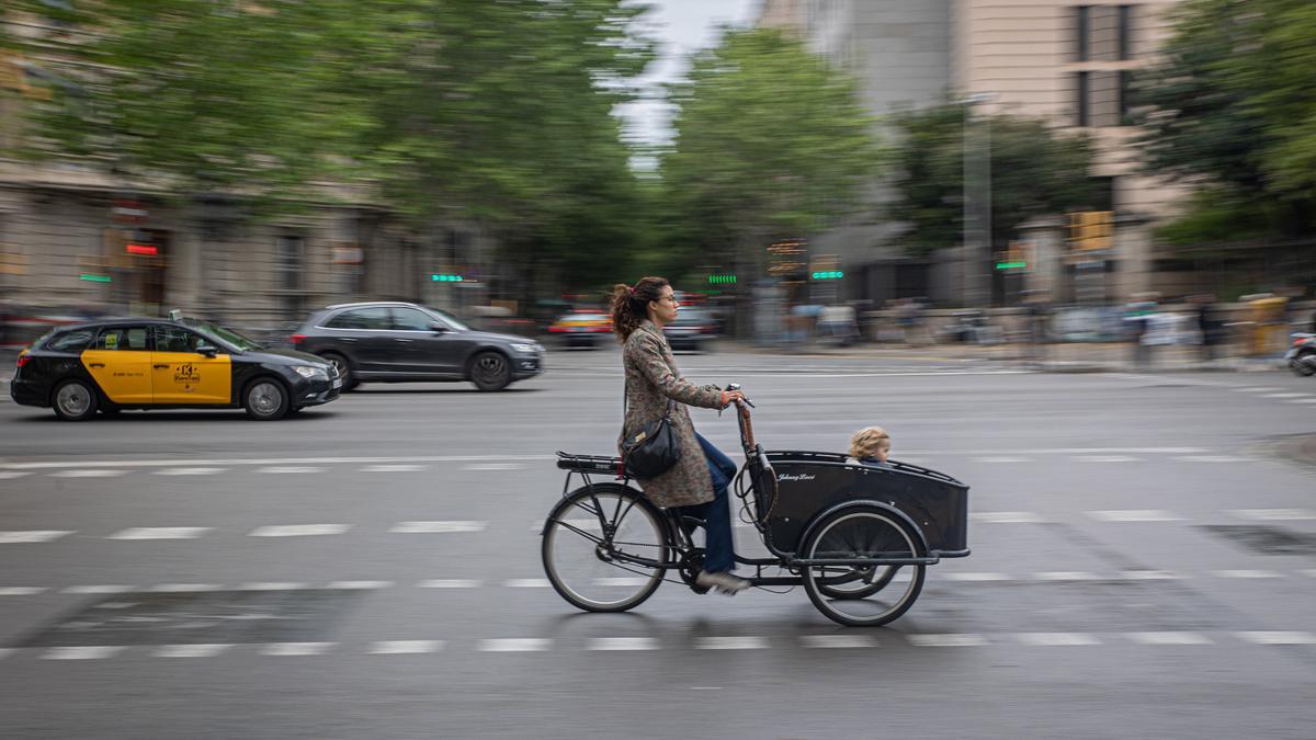 Un madre lleva su hijo en una 'cargo bike' por la Gran Via, este miércole