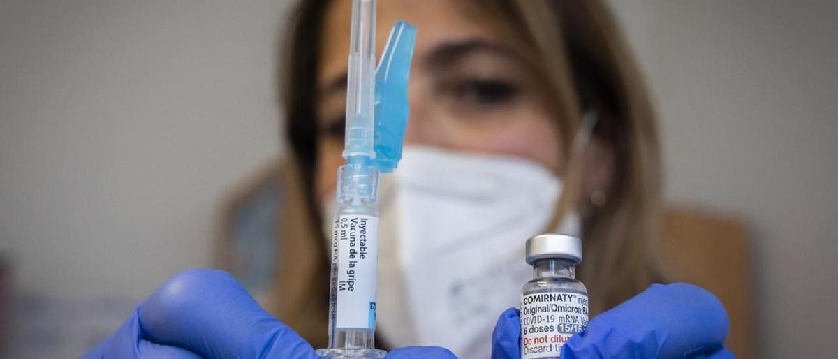 Una sanitaria muestra una vacuna contra la gripe y el covid-19
